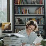 A young man focuses on studying amidst a bookstore environment, surrounded by books.