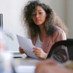 Confident businesswoman reviewing documents in modern office setting, focused and professional.